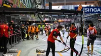 Anggota tim Ferrari menyapu pit lane setelah hujan sebelum&nbsp;balapan Formula 1 (F1) GP Singapura di Sirkuit Jalan Raya Marina Bay, Minggu, 2 Oktober 2022. (MOHD RASFAN / AFP)