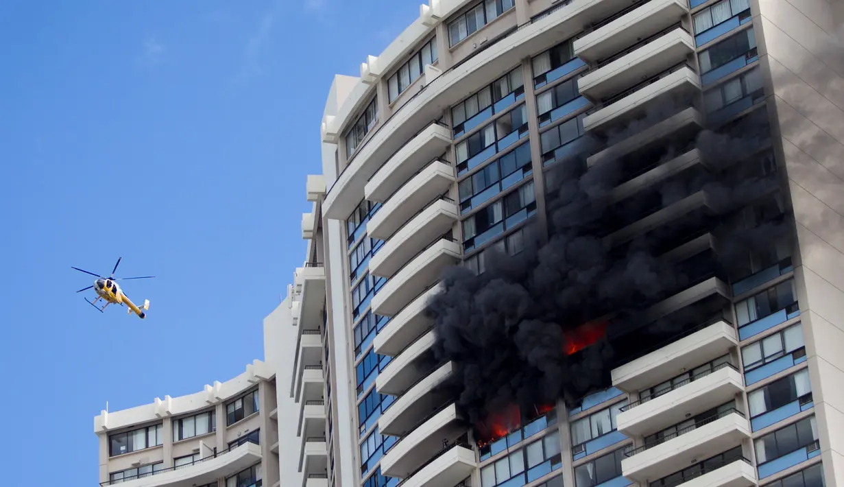 Petugas mengerahkan helikopter untuk membantu proses evakuasi kebakaran yang terjadi di apartemen Marco Polo, Honolulu (14/7). Hingga saat ini tim pemadam kebakaran masih terus berusaha menjinakkan api di apartemen tersebut. (AP Photo / Marco Garcia)