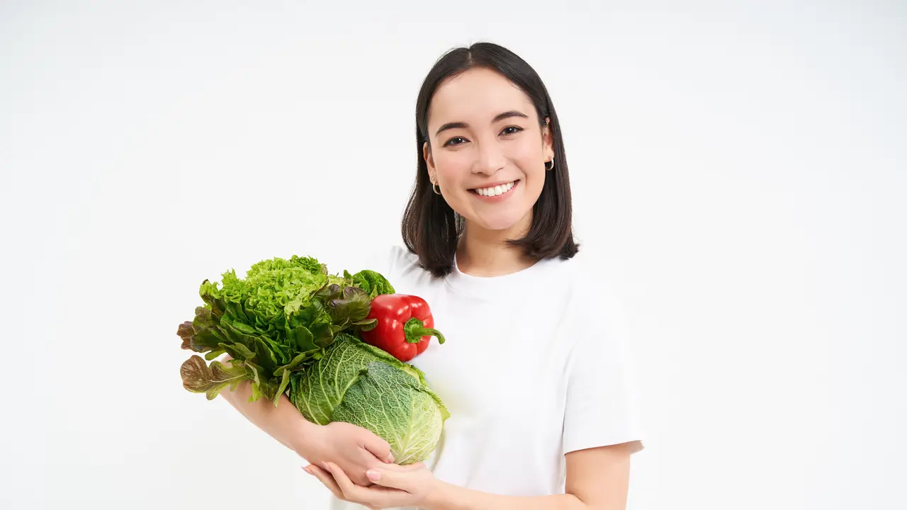 Seorang perempuan memegang sayur-sayuran di tangannya (Foto Dok: Freepik/benzoix)