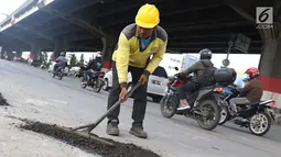 Petugas menambal lubang pada jalan yang rusak di kawasan Jatinegara, Jakarta, Kamis (7/2). Musim hujan yang mengguyur Jakarta selama beberapa waktu terakhir meninggalkan kerusakan pada sejumlah ruas jalan di Ibukota. (Liputan6.com/Immanuel Antonius)