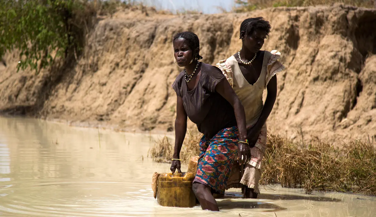 Mary Abong (kiri) dan Alissa Lual mengambil air dari lokasi proyek pembangunan jalan, Sudan Selatan (22/11). Sebelumnya, sekitar 4.000 orang meninggalkan desa akibat pertempuran antara pemerintah dan kelompok milisi. (AFP Photo/Albert Gonzalez Farran)