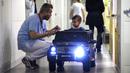 Petugas medis melihat Souvail (2) menggunakan mobil mainan listrik menuju ruang operasi di Rumah Sakit Valenciennes, Prancis, Jumat (2/2). Program ini untuk membuat anak-anak lebih santai sebelum menjalani prosedur operasi. (FRANCOIS LO PRESTI/AFP)