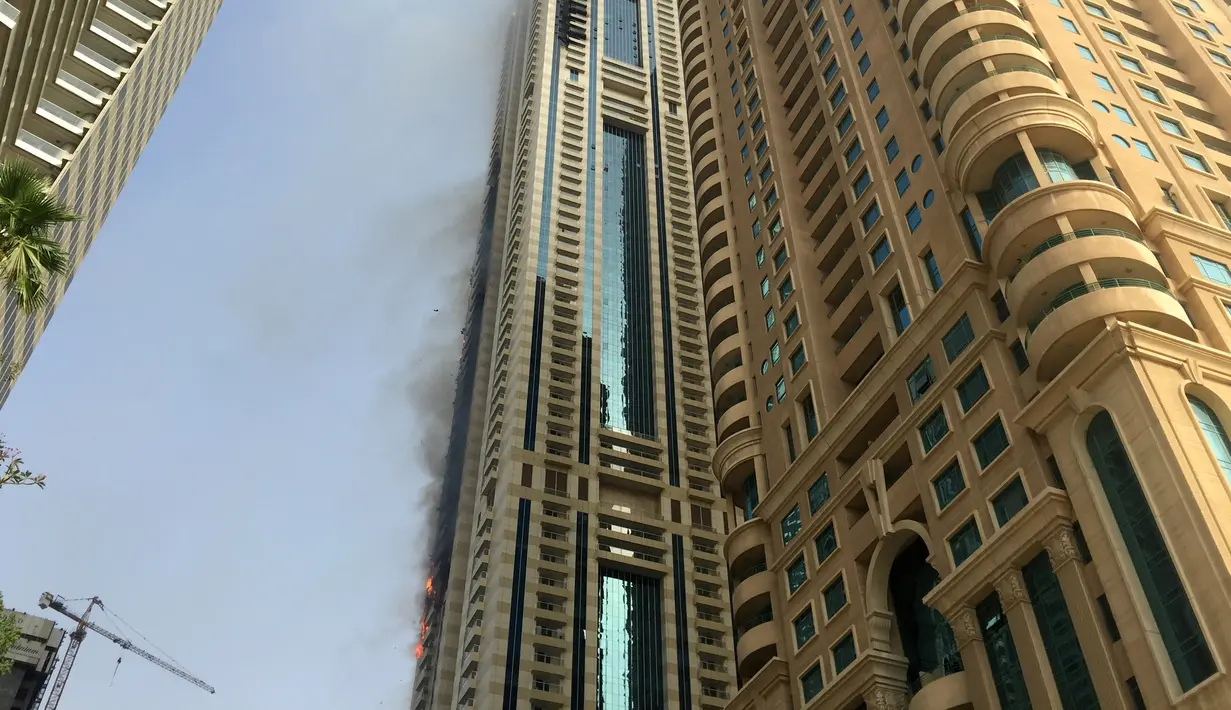 Sebuah gedung pencakar langit terbakar di distrik Marina Dubai, Rabu (20/07). Menurut laporan, kobaran api terlihat di Sulafa Tower (gedung 288 meter) dan api dengan cepat menyebar akibat hembusan angin. (Mohamed HASNI/AFP)