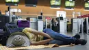 Seorang penumpang maskapai Viva Air tidur di bandara setelah maskapai berbiaya rendah itu menangguhkan operasinya di Bandara Internasional El Dorado di Bogota, Kolombia, Selasa (28/2/2023). Maskapai sedang menunggu penyelesaian proses integrasi dengan sekelompok maskapai penerbangan yang harus disetujui oleh otoritas Kolombia. (AP Photo/Fernando Vergara)