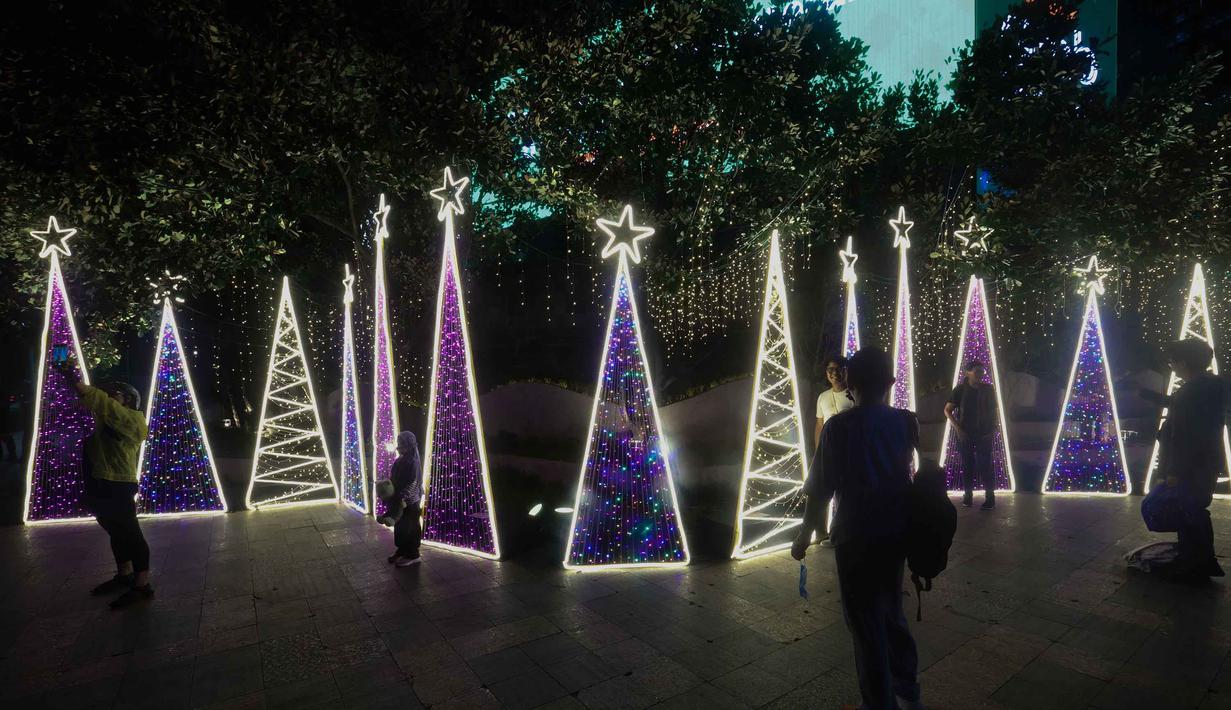 Jakarta Light Festival dijadwalkan berlangsung hingga Sabtu 27 Desember 2025 setiap pukul 18.00 hingga 22.00 WIB. Tampak dalam foto, warga menikmati suasana Jakarta Light Festival 2025 di sekitar Bundara Hotel Indonesia, Jakarta, Selasa (23/12/2025). (Kapanlagi.com/Budy Santoso)
