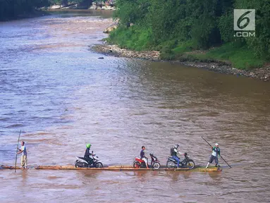Sebuah rakit mengangkut motor dan warga menyeberangi Sungai Cisadane di Rumpin, Bogor, Selasa (13/3). Mereka terpaksa menaiki rakit akibat jembatan Gerendong yang merupakan akses jalan utama Ciseeng -Rumpin masih dalam perbaikan. (Merdeka.com/Arie Basuki)