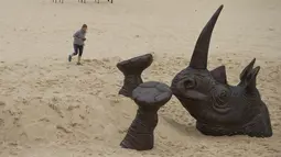 Pengunjung mengambil gambar patung kepala badak raksasa yang dipamerkan di pantai Tamarama di Sydney, Rabu (19/10). Pameran yang bernama ‘Sculpture by the sea’ merupakan pameran patung tahunan diluar ruangan yang terbesar di Australia. (PETER PARKS/AFP)