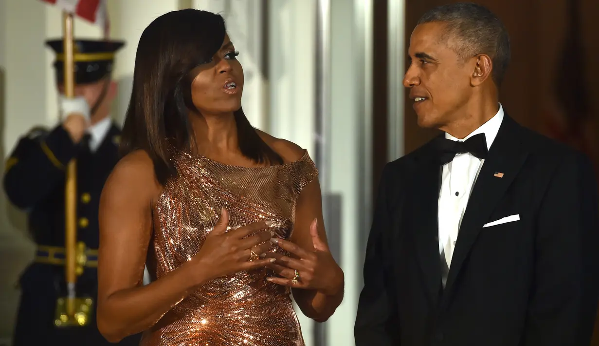 Presiden AS Barack Obama didampingi Ibu Negara Michelle Obama menunggu kedatangan PM Italia Matteo Renzi di Gedung Putih, Washington, Selasa (18/10). Michelle memakai gaun berwarna rose-gold yang dibuat khusus oleh Atelier Versace. (Nicholas Kamm/AFP)