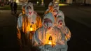 Orang-orang yang mengenakan pakaian pelindung putih membawa lilin selama upacara peringatan yang didedikasikan untuk petugas pemadam kebakaran dan pekerja yang meninggal setelah bencana nuklir Chernobyl, menjelang peringatan 40 tahunnya di Slavutych, Ukraina, Sabtu, 25 April 2026. (AP Photo/Dan Bashakov)