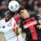 Pemain Bayer Leverkusen, Piero Hincapie, duel udara dengan pemain Union Berlin, David Datro Fofana, pada laga Bundesliga di Bay Arena, Minggu (12/11/2023). (AFP/Ina Fassbender)