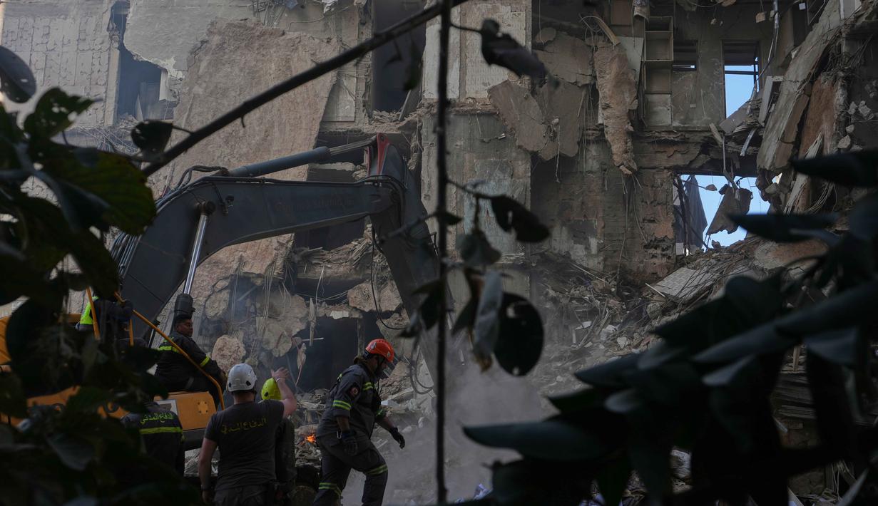 Dengan menggunakan 50 jet tempur, serangan Israel menghantam 100 target dalam waktu hanya 10 menit. Tampak dalam foto, para pekerja pertahanan sipil Lebanon dan sebuah ekskavator membersihkan puing-puing di lokasi bangunan yang hancur akibat serangan udara Israel sehari sebelumnya di pusat kota Beirut, Lebanon, Kamis 9 April 2026. (AP Photo/Hassan Ammar)