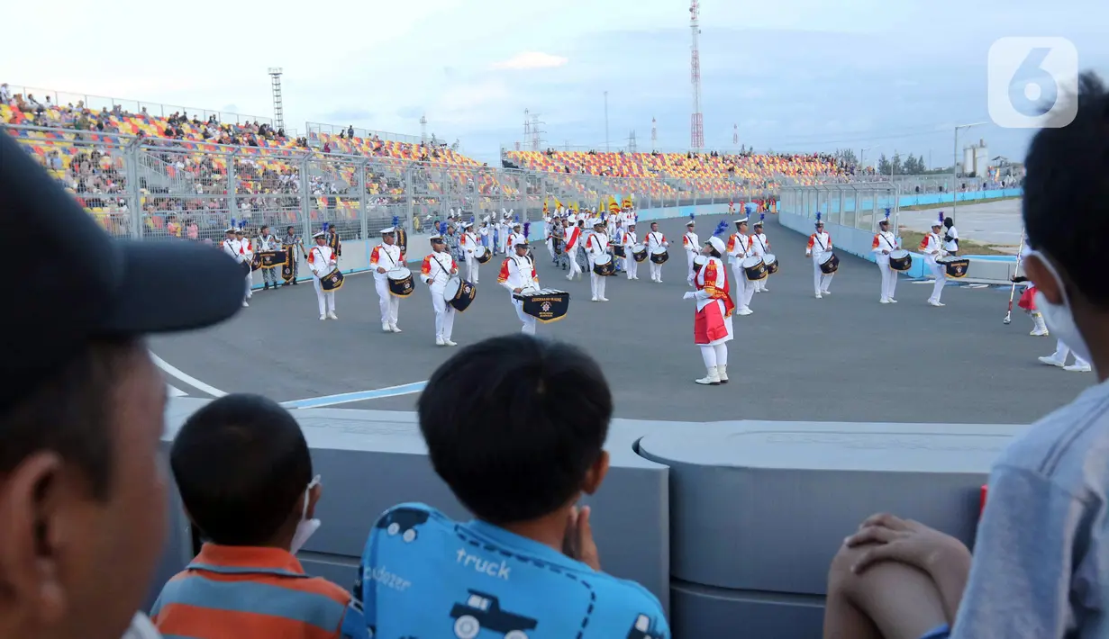 Penonton menyaksikan parade dalam pagelaran Jakarnaval 2022 di Jakarta International Eprix Circuit, Ancol, Minggu (14/8/2022). Gelaran Jakarnaval 2022 yang mengangkat tema "Kekayaan Intelektual Nusantara untuk Dunia" tersebut menampilkan parade komunitas pegiat seni budaya, marching band, dan kendaraan hias. (Liputan6.com/Herman Zakharia)