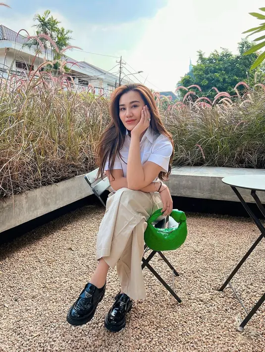 Gaya chic nan stylish Aaliyah Massaid menikmati sore. Tampilan kasual penuh gaya, Aaliyah tampak mengenakan atasan putih berkerah lengan pendek, dipadu celana beige, platform hitam, dan handbag hijau. [Foto: Instagram/aaliyah.massaid]