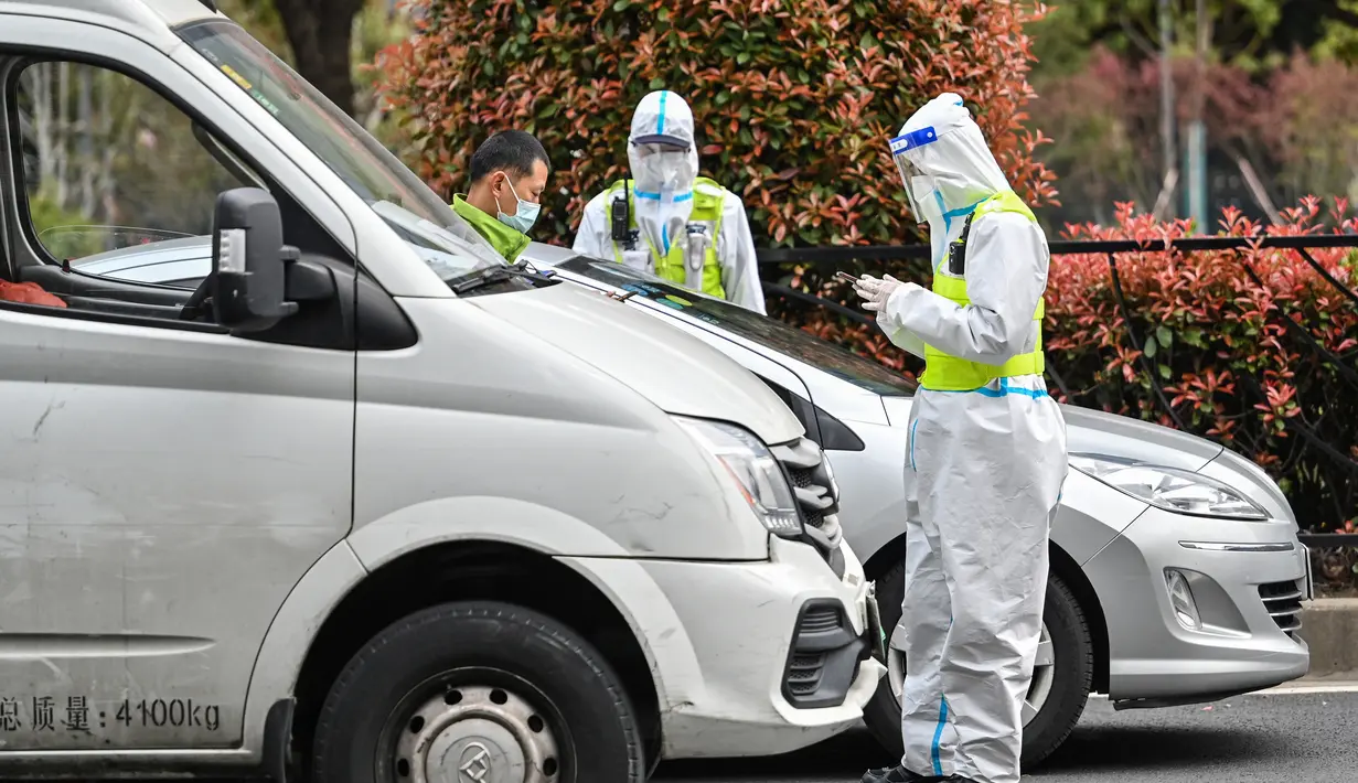 Petugas polisi yang mengenakan pakaian pelindung mengontrol akses ke terowongan ke arah distrik Pudong yang dikunci sebagai tindakan melawan virus corona Covid-19, di Shanghai (28/3/2022). (AFP/Hector Retamal)