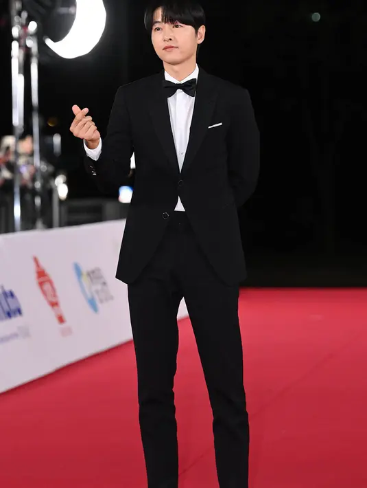 Song Joong Ki tampil gagah dengan setelan jas dan celana panjang hitam. Kemeja putih dilengkapi dengan dasi kupu-kupu hitam menyempurnakan penampilannya secara keseluruhan. [Foto: soompi.com]