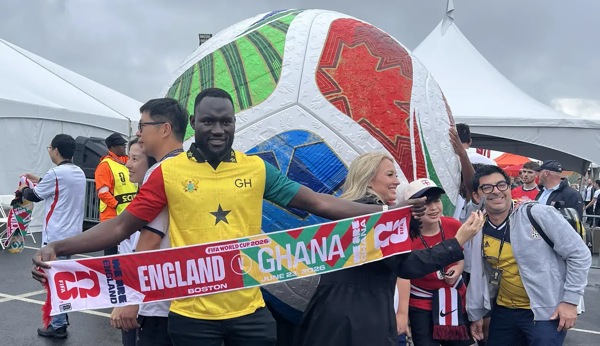 Seorang suporter Ghana membentangkan syal saat berpose di depan instalasi bola raksasa Piala Dunia 2026 di area Gillette Stadium, Foxborough, Boston, AS, Senin (23/6/2026). Antusiasme suporter kedua tim mewarnai laga fase grup Piala Dunia 2026 antara Inggris dan Ghana. (KLY Sports/Hery Kurniawan)