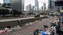 Orang-orang berjalan di jalan yang penuh sampah sehari setelah demonstrasi menolak RUU ekstradisi di Hong Kong (13/6/2019). Aksi tersebut berujung bentrok antara polisi dan warga dimana puluhan ribu orang memblokir jalan-jalan di kota tersebut. (AFP Photo/Anthony Wallace)