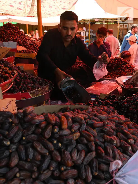 Seorang penjual melayani pembeli kurma memasuki bulan suci Ramadan di pasar mingguan di Islamabad, Pakistan pada 5 Mei 2019. Buah khas Timur Tengah, kurma, selama Bulan Ramadan ramai diburu untuk dihidangkan saat berbuka puasa. (Photo by AAMIR QURESHI / AFP)