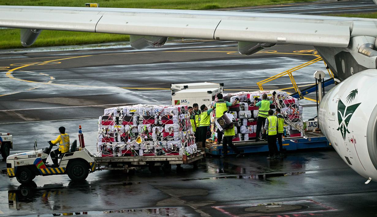 Para pekerja memuat barang bawaan jamaah haji Indonesia ke pesawat Saudia Airlines sebelum diberangkatkan di Bandara Internasional Juanda, Sidoarjo, Jawa Timur, Rabu 22 April 2026. (JUNI KRISWANTO/AFP)