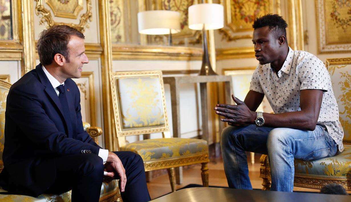 Presiden Prancis Emmanuel Macron (kiri) berbincang dengan Mamoudou Gassama di Istana Elysee, Paris, Prancis, Senin (29/5). Imigran asal Mali tersebut memperoleh penghargaan setelah menyelamatkan seorang balita di Paris. (AP Photo/Thibault Camus, Pool)