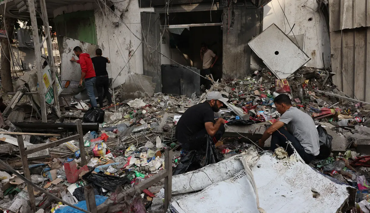 Warga Palestina mencari puing-puing bangunan untuk mencari barang-barang yang masih bisa diselamatkan setelah serangan udara Israel di Kota Gaza pada tanggal 11 Oktober 2023. (Mohammed ABED/AFP)