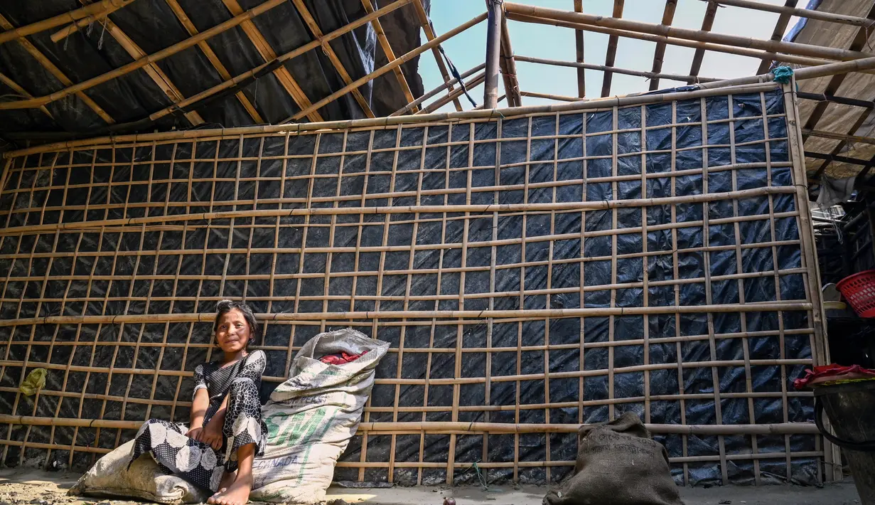 Seorang gadis duduk di dalam rumahnya yang sebagian dihancurkan oleh topan Mocha, di pulau Shahpori di pinggiran Teknaf, Bangladesh, Senin (15/5/2023). (Photo by Munir uz zaman / AFP)