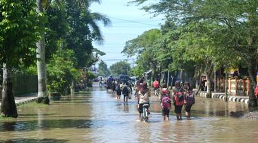 Anak sekolah melintasi genangan banjir di Sidareja, Cilacap, Jawa Tengah. (Foto: Liputan6.com/Muhamad Ridlo)