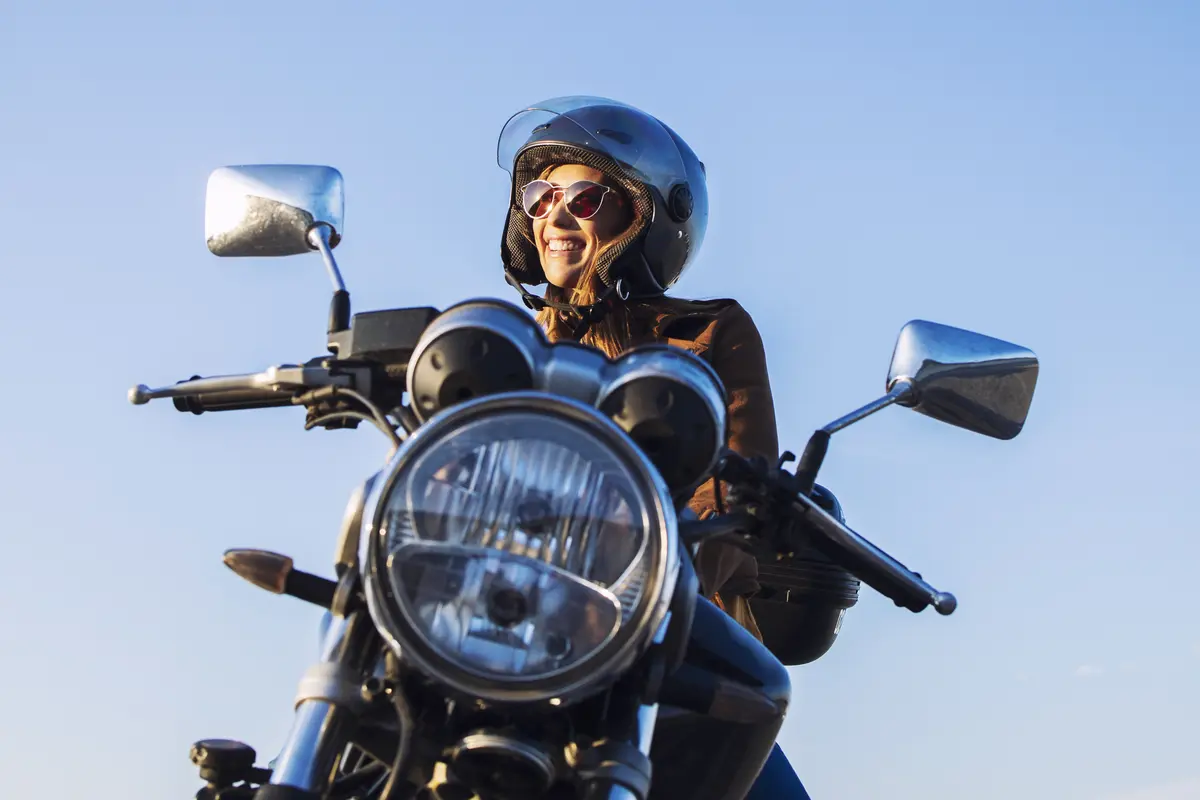 Pengendara motor wanita memakai helm dan mengendarai sepeda motor