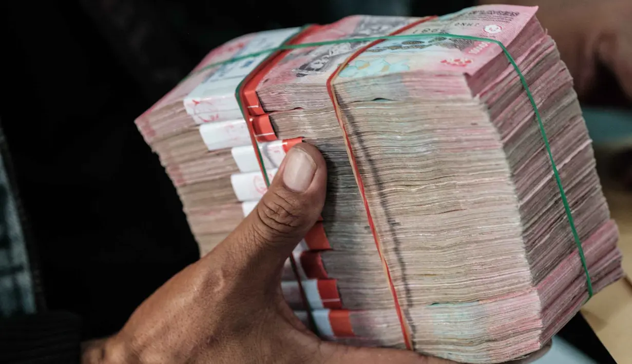 Seorang pria menerima bungkusan uang kertas rupiah di salah satu kantor penukaran, Jakarta, Kamis pada 4 Juni 2026. (Yasuyoshi Chiba/AFP)