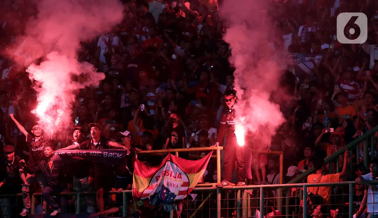 Suporter menyalakan flare saat menyaksikan laga Persija melawan Sabah FC pada laga uji coba internasional di Stadion Patriot Candrabhaga, Kota Bekasi, Minggu (5/6/2022). Pertandingan sepakbola kembali bisa disaksikan secara langsung setelah pemerintah melonggarkan aturan pemakaian masker di luar ruangan. (Liputan6.com/Helmi Fithriansyah)