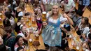 Seorang wanita menunjukkan gelas berisi bir bersama rekan-rekannya saat mengikuti festival minum bir tahunan dalam pembukaan Oktoberfest ke-182 di Munich, Jerman (16/9). (AFP Photo/dpa/Sven Hoppe/Germany Out)