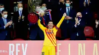 Striker Barcelona, Lionel Messi, mengangkat trofi usai menjuarai Copa del Rey di Stadion Olimpico de Sevilla, Minggu (18/4/2021). Barcelona menang 4-0 atas Athletic Bilbao. (AFP/Cristina Quicler)