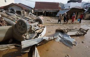 Penting dicatat, Kabupaten Aceh Tamiang merupakan salah satu wilayah yang mengalami dampak paling parah setelah dihantam banjir bandang dan longsor pada Rabu (26/11/2025) lalu. Warga sangat membutuhkan pasokan bantuan kebutuhan dasar air bersih, listrik, hingga jaringan komunikasi. Tampak dalam foto, para penyintas berjalan melewati reruntuhan mobil di area terdampak banjir bandang di Aceh Tamiang, Sumatera, Kamis 4 Desember 2025. (AP Photo/Binsar Bakkara)