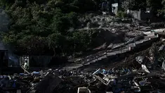 Seorang pekerja membawa balok kayu selama operasi pembongkaran kota kumuh distrik "Talus 2" di Koungou, di pulau Mayotte, Samudra Hindia Prancis, pada 23 Mei 2023. (AFP/PHILIPPE LOPEZ)