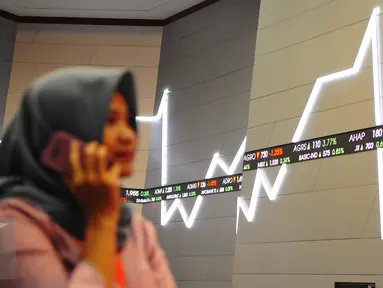 Pengunjung melintasi layar pergerakan saham di Bursa Efek Indonesia, Jakarta, Jumat (10/2). (Liputan6.com/Angga Yuniar)