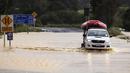 Sebuah kendaraan darurat membawa perahu karet melintasi jalan yang terendam banjir di Cook's Beach, sebelah timur Auckland, Selandia Baru, Selasa (14/2/2023). Badai itu pun makin parah mulai Senin dan Selasa pagi hingga seluruh negara bagian mendapat status Keadaan Darurat, menurut para pejabat. (Mike Scott/New Zealand Herald via AP)