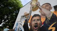 Seniman Maxi Bagnasco melukis mural yang menggambarkan kapten dan penyerang Argentina Lionel Messi mengangkat Trofi Piala Dunia 2022 di samping rekan satu timnya setelah memenangkan turnamen Piala Dunia Qatar 2022 di Buenos Aires pada 22 Desember 2022. (AFP/Luis Robayo)
