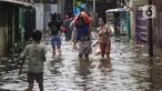 Warga melintasi banjir di salah satu permukiman penduduk di Kawasan Cengkareng Barat, Jakarta Barat, Kamis (30/1/2025). (Liputan6.com/Angga Yuniar)