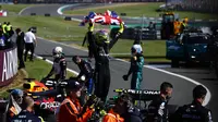 Pembalap Mercedes, Lewis Hamilton membentangkan benedera Inggris saat merayakan kemenangan di Formula 1 GP Inggris 2024 yang berlangsung di Sirkuit Silverstone, Inggris, Minggu (08/07/2024). (AFP/Benjamin Cremel)