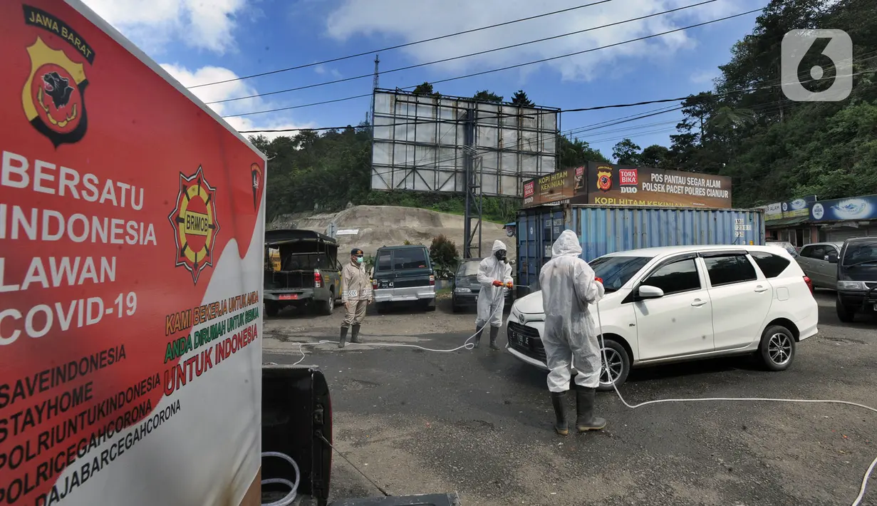 Anggota Batalyon B Brimob Cipanas melakukan penyemprotan disinfektan saat penyekatan arus lalu lintas di kawasan Ciloto, Cianjur, Jawa Barat, Jumat (17/4/2020). Penyemprotan yang dilakukan selama 20 hari tanpa henti ini untuk mencegah penyebaran virus corona COVID-19. (merdeka.com/Arie Basuki)