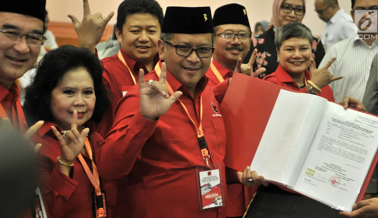 Sekjen PDIP Hasto Kristiyanto (tengah) menunjukkan daftar bakal caleg ke KPU di Jakarta, Selasa (17/7). Hasto tampak beberapa kali mengacungkan salam metal. (Merdeka.com/Iqbal Nugroho)