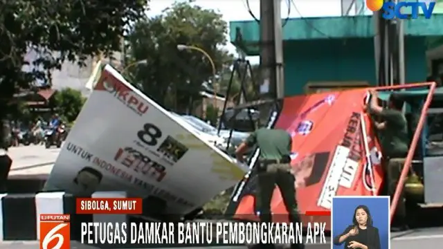 Petugas harus menggunakan tangga mobil pemadam kebakaran untuk menjangkau baliho.