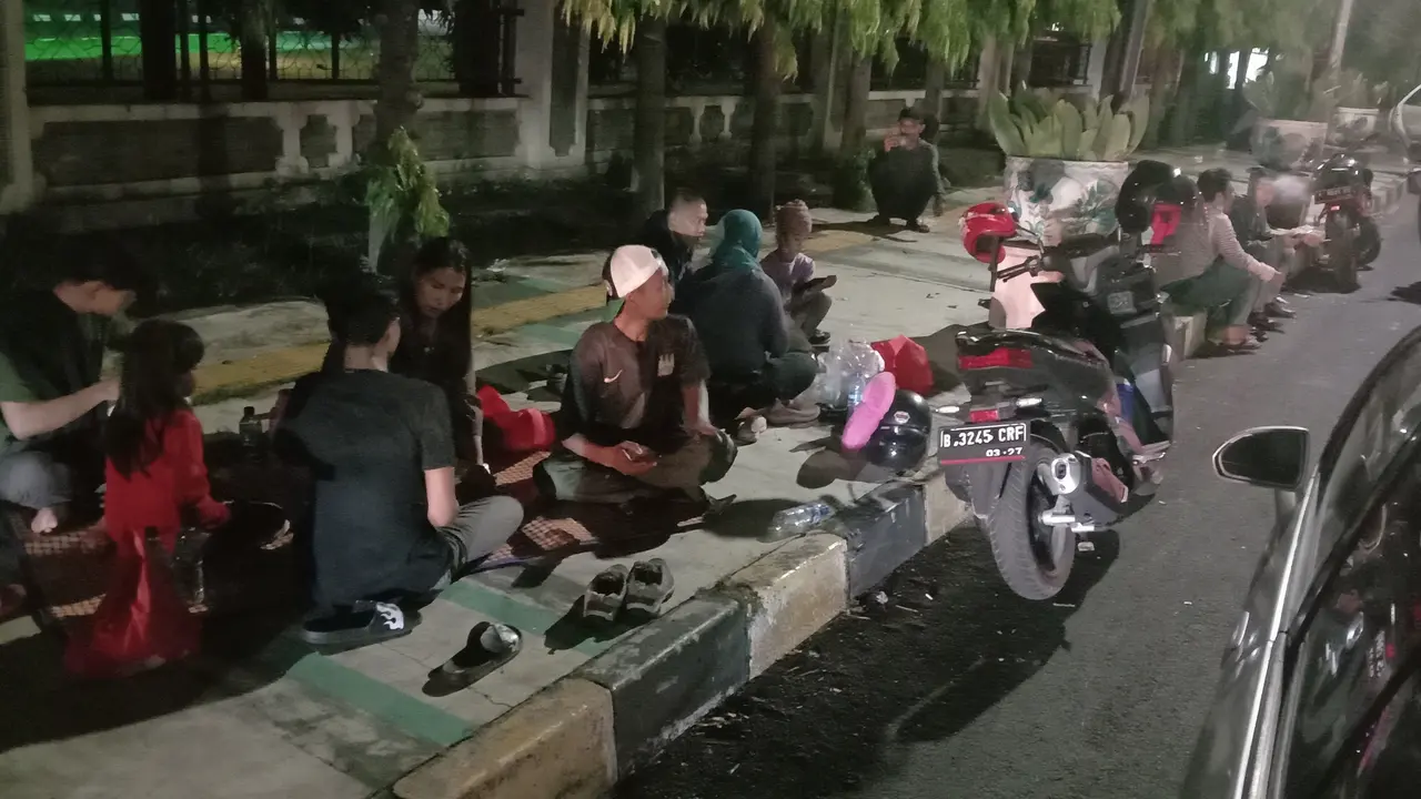 Sejumlah pemudik Lebaran 2022 terpaksa makan sahur di trotoar lantaran jalan arteri di Kota Cilegon, Banten menuju Pelabuhan Merak macet panjang sejauh 10 km, Jumat (29/4/2022). (Liputan6.com/Yandhi Deslatama)