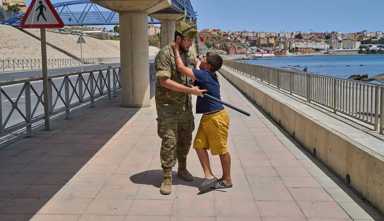 Seorang anak berusia 12 tahun yang menyeberang ke Spanyol tanpa didampingi orang dewasa dikawal oleh seorang tentara Spanyol ke perbatasan Spanyol-Maroko sementara anak itu memohon agar tidak dikirim kembali ke Maroko dari wilayah kantong Spanyol di Ceuta, Senin, 3 Agustus 2026. (Foto AP/Bernat Armangue)