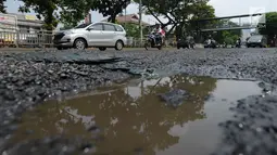 Sejumlah kendaraan melewati jalan berlubang yang masih tergenang air di ruas Jalan Lapangan Ros, Tebet, Jakarta, Sabtu (11/5/2019). Jalan-jalan berlubang yang terisi air tersebut dapat mengakibatkan kecelakaan bagi pengendara kendaraan bermotor. (merdeka.com/Imam Buhori)