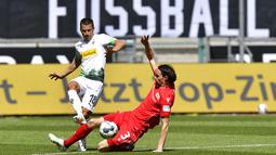 Pemain Borussia Moenchengladbach, Stefan Lainer, berebut bola dengan pemain Union Berlin, Neven Subotic, pada laga Bundesliga di Stadion Borussia-Park, Minggu (31/5/2020). Moenchengladbach menang 4-1 atas Union Berlin. (AP/Martin Meissner)