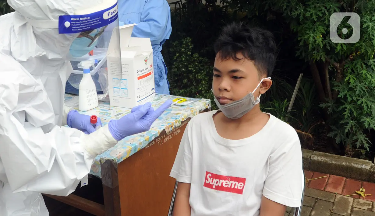 Seorang anak bersiap menjalani swab test massal di Puskesmas Ciganjur, Jakarta Selatan, Kamis (7/1/2020). Swab test gratis yang diadakan oleh Sudinkes Jakarta Selatan tersebut dilakukan terhadap puluhan warga. (merdeka.com/Arie Basuki)