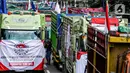 Salah satu peserta aksi terlihat di antara truk-truk saat unjuk rasa terkait Rancangan Undang Undang (RUU) nol kelebihan muatan dan dimensi atau Zero Over Dimension Over Load (ODOL) memasang spanduk di Jalan Medan Merdeka Selatan, Jakarta, Rabu (2/7/2025). (Liputan6.com/Herman Zakharia)