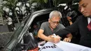 Sebelum meninggalkan Gedung KPK, Iwan Fals sempat menandatangani spanduk yang dibawa aktivis Permindo (Perwakilan Revousi Mental Indonesia), Jakarta, Senin (29/12/2014). (Liputan6.com/Miftahul Hayat)