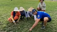 Pembalap WSBK dari tim Pata Yamaha Toprak Razgatlioglu mengarit rumput bersama pekerja di dekat area Sirkuit Mandalika. (foto: Youtube GPABC)